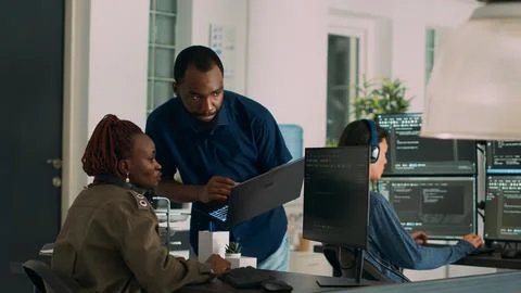 Team of software developers talking about source code running on laptop Stockfoto's