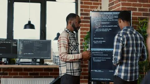 Team of software programmers leaving after analyzing source code on wall screen Stock Photos