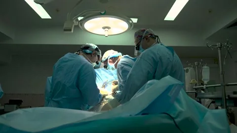 A team of surgeons leaned over the operating table during a complex operation. Stock Footage 303409987