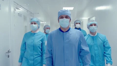 Team of surgeons in masks and protective workwear walking down the hospital Stock Footage 200855967