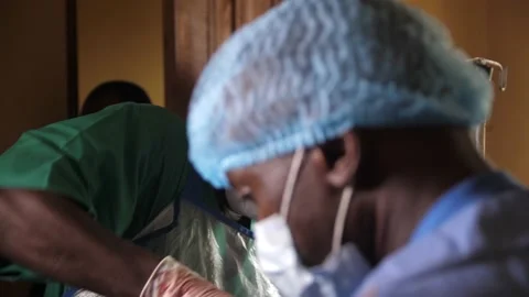 Team of surgeons in operating theater performing operation on a patient . Видео 165383864