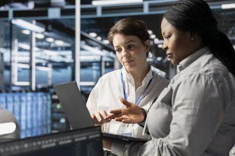 Team of system administrators in data center using laptop to update software Stockfoto's