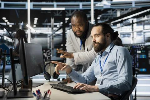 Team of system administrators using computer in server farm, analyzing data 스톡 사진