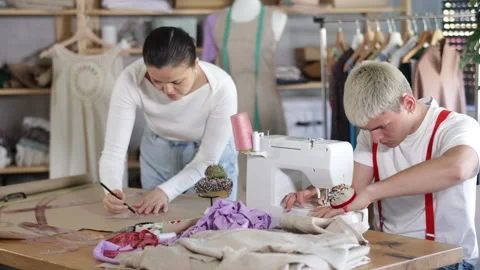 Team of tailors works in a workshop: a man sews a sample of clothes on a machine Stock Footage 326314806