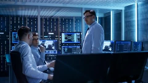 Team of Technical Moderators Have Discussion in Monitoring Room. System Contr Foto stock