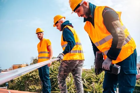 Team of technical workers work on the roof of a house Stock Photos