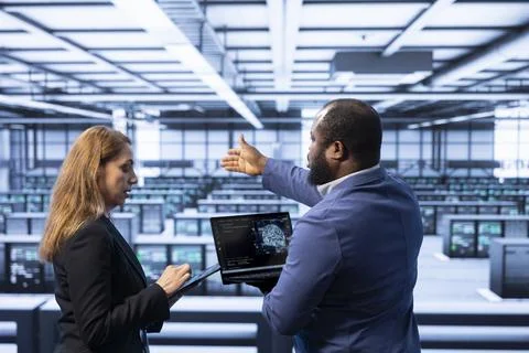 Team of technicians in data center using laptop to visualize AI Stock Photos