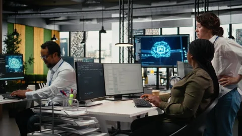 Team of technicians in office working together, automating workflows using AI Stock Footage 323333130