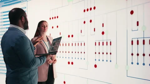 Team of technicians review PCB layout, using laptop to project it on screen Stock Footage 330030479