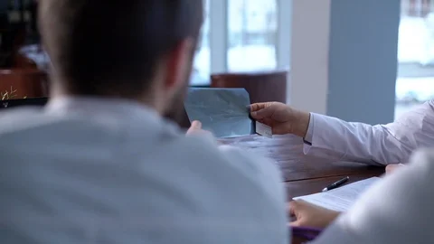 Team of three doctors discuss an X-ray of a patient in the consulting room. Stock Footage 124921429