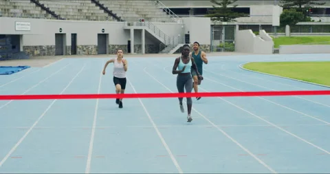 Team of track runners running to a finish line to win in competitive sports Stock Footage