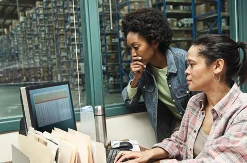 Team of two African American female warehouse workers working on a computer in Stock Photos
