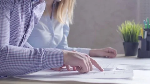 Team of two architects, sitting at desk in office with building plans 스톡 동영상 72985344