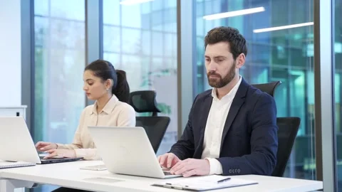 Team of two co-workers, a man and a woman working on laptop computers sitting  Stock Footage 309011313