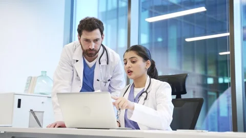 A team of two doctors having a professional discussion in office with a laptop.  Stock Footage 309011650