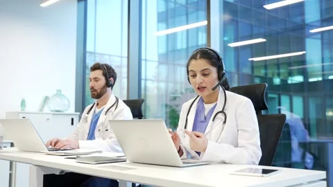 A team of two doctors in headset working in online call center healthcare servic Video stock 298996425