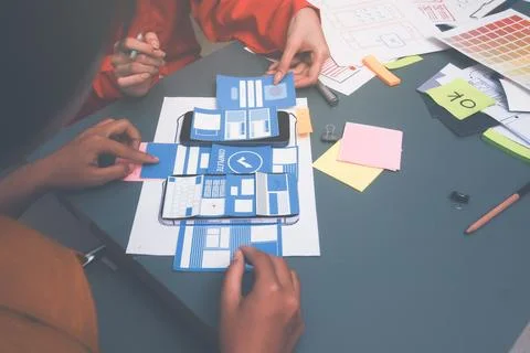 Team of uxui designers pointing at computer screen, discussing new mobile a.. Foto stock