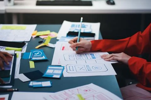Team of uxui designers pointing at computer screen, discussing new mobile a.. Stock Photos