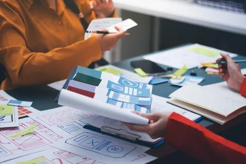 Team of uxui designers pointing at computer screen, discussing new mobile a.. Stock Photos