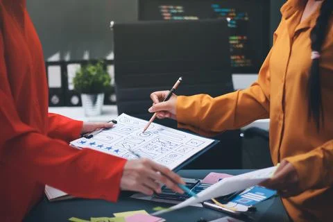 Team of uxui designers pointing at computer screen, discussing new mobile a.. Stock Photos