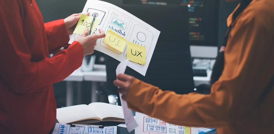 Team of uxui designers pointing at computer screen, discussing new mobile a.. Stock Photos