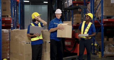 Team of warehouse workers lifting package and exchanging information while Stock Footage 307852293