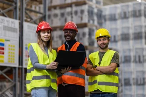 Team of warehouse workers reviewing logistics data on a laptop Stock Photos