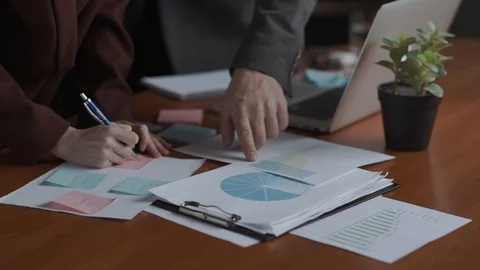 Team work on analysis and reports. Postits, graphs, pie chart, bar chart hands Video stock 129943068