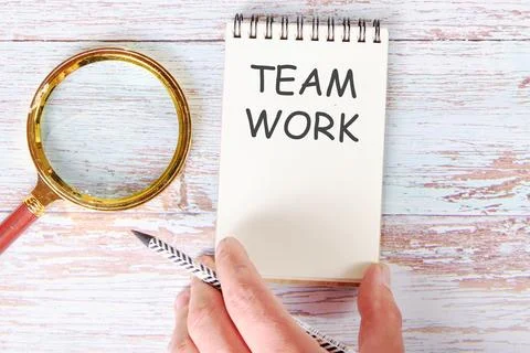 TEAM WORK written on a blank sheet of a notebook which is touched by a man's  Stock Photos