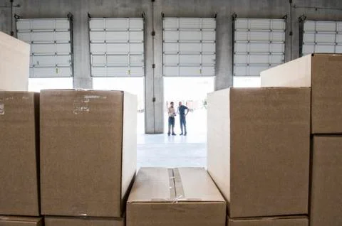 Team of workers check out inventory in front of loading dock doors in a new Stock Photos