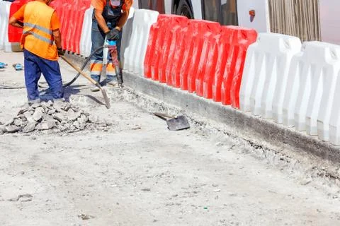 A team of workers cleans some of the concrete with a jackhammer during road c Stock Photos