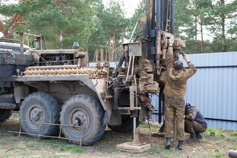 Team of workers with drilling rig on car are drilling artesian well for wat.. Stock Photos