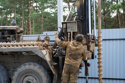 Team of workers with drilling rig on car are drilling artesian well for wat.. Stock Photos