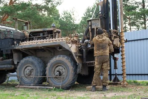 Team of workers with drilling rig on car are drilling artesian well for wat.. Stock Photos