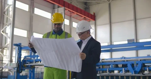 Team of workers at heavy industry enterprise discuss layout in blueprint Stock Footage 121101205