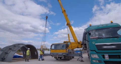 A team of workers in overalls and helmets help a large yellow truck crane  Stock Footage 161962389