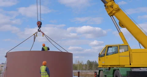 A team of workers in overalls and helmets help a large yellow truck crane Stock Footage 161963093