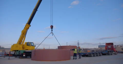 A team of workers in overalls and helmets help a large yellow truck crane Stock Footage 161965945