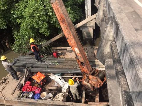 Team of workers pull the concrete pillars out of the water on the pontoon Stock Photos