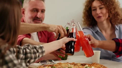 A team of workers sits at a table and clinks glasses with glass bottles Stock Footage 243366308