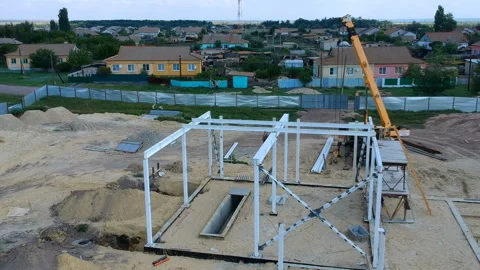 A team of workers using a crane builds a house frame from metal beams Stock Footage 119498139