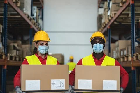 Team working in warehouse loading delivery boxes while wearing face mask Foto stock