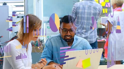 Team writing and typing at laptop as data graphics appearing on glass, aiding Stock Footage 333704446