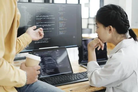 Team of young computer programmers cooperating while working on desktop PC in Stockfoto's