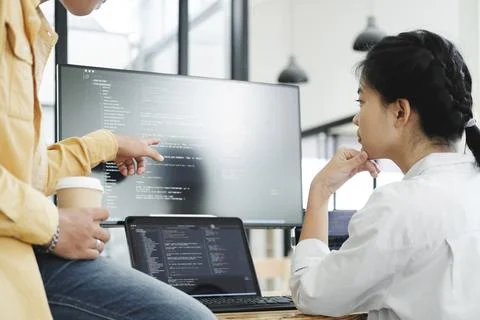 Team of young computer programmers cooperating while working on desktop PC in Stock-Fotos