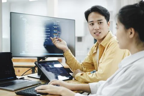 Team of young computer programmers cooperating while working on desktop PC in Stock-Fotos