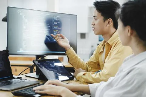 Team of young computer programmers cooperating while working on desktop PC in Stock-Fotos