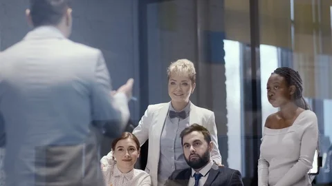 A team of young creative multi-ethnic businessmen sits at a table in a meeting Stock Footage 123450598