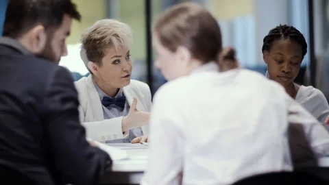 A team of young creative multi-ethnic businessmen is sitting at a table in a Stock Footage 123451226