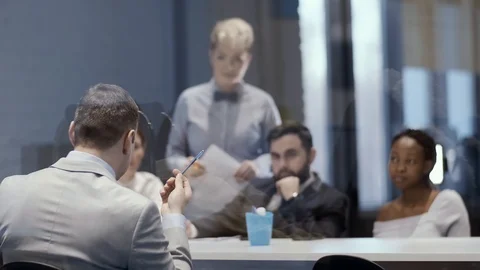 A team of young creative multinational businessmen sits at a table and listens Stock Footage 123450618